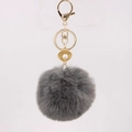 Close-up of gray faux fur pompom keychain with golden shell pendant and pearl detail - Dark Gray