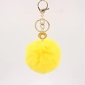 Detailed close-up of fluffy yellow faux fur keychain with gold shell and pearl accent - Yellow
