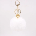 Detailed close-up of fluffy white pom-pom keychain with gold shell and pearl charm - White