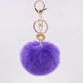 Detail of purple faux fur pompom keychain with golden shell and pearl charm accessory - Deep purple