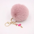 Detalle de llavero con pompón rosa y un colgante de flamenco en metal dorado - Rosa Viejo
