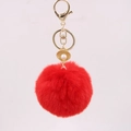 Detalle de llavero con pompón rojo, dije de concha dorada y una perla blanca - Rojo