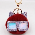 Détail d'un porte-clés pompon rouge avec oreilles pailletées et lunettes irisées - Bordeaux