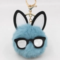 Detail of blue plush bunny keychain with black frame glasses and golden lobster clasp - Teal
