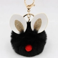 Detail of a fluffy black pompom keychain with festive bunny ears and golden metal hardware - Bunny Ear Pom Pom Keychain / Black