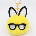 Macro shot of yellow pompom keychain with long bunny ears and black glasses frame - Yellow