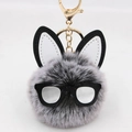 Detailed view of plush rabbit ear keychain with black rim glasses and faux fur ball - Two-tone Black