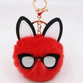 Macro view of a red fluffy pompom keychain featuring long ears and black glasses frame - Red
