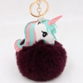 Close-up of fluffy faux fur unicorn keychain with gold metal ring and colorful leather detail - Purplish Red