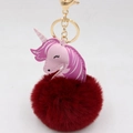 Detail of a pink unicorn keychain with a deep red fluffy pom pom and gold metal clasp - Gold Keychain / Burgundy