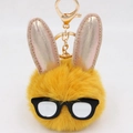 Détail d'un porte-clés lapin jaune en peluche avec oreilles pailletées et lunettes - Orange