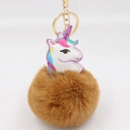 Nahaufnahme von flauschigem braunem Kunstpelz-Bommel und Einhorn-Anhänger aus Leder - Goldener Schlüsselanhänger / Kaffeebraun