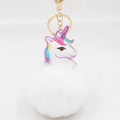 Detailaufnahme von flauschigem Plüsch-Pompon und goldenem Einhorn-Schlüsselanhänger - Goldener Schlüsselanhänger / Weiß