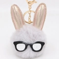 Vue détaillée du porte-clés lapin en peluche avec pompon gris et oreilles dorées - Gris clair
