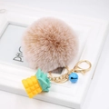 Macro view of fluffy brown pom-pom and yellow resin pineapple charm with gold keychain - Mixed Khaki