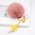 Close-up of pink fur pompom keychain with a golden banana pendant and a yellow bell - Dusty Pink
