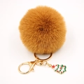 Détail d'un porte-clés pompon marron avec fermoir doré et pendentif sapin de Noël - Café