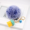 Detail of purple faux fur pompom keychain with yellow pineapple charm and blue bell - Double Blue