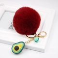 Detailed close-up of a red plush ball keychain with avocado charm and blue bell accent - Avocado Keychain / Burgundy