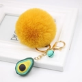 Detailed macro view of a fluffy yellow pompom keychain with a cute avocado charm - Avocado Keychain / Orange