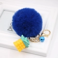 Detail of blue faux fur pompom keychain with golden pineapple charm and small bell - Sapphire Blue