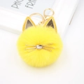Detailed close-up of yellow plush cat keychain with golden ears and metal whiskers - Yellow