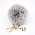 Détail macro d'un porte-clés pompon gris en fausse fourrure avec un charme de sapin de Noël - Bicolore Gris