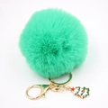Gros plan du porte-clés pompon vert menthe avec un pendentif d'arbre de Noël doré - Vert Herbe