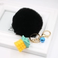 Detail of black faux fur pompom keychain with yellow pineapple and blue bell - Black