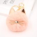 Close-up of pink plush cat keychain with golden metal whiskers and heart-shaped nose - Pink