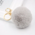 Detail showing the fluffy grey faux rabbit fur pompom and shiny golden lobster clasp hardware - Light Gray