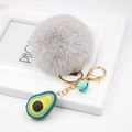 Detail of grey faux fur pompom keychain with a green avocado pendant and golden metal ring - Avocado Keychain / Light Gray