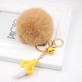Detail view of khaki faux rabbit fur pom pom keychain with a yellow banana pendant and bell - Khaki