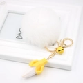 Close-up of fluffy white pompom keychain with a resin banana and gold bell charm - White