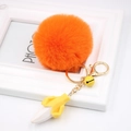 Close-up of fluffy orange pompom keychain with banana charm and golden lobster clasp - Orange