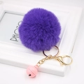 Detail of soft purple faux fur pompom keychain with golden clasp and pink bell - Deep purple