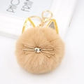 Detailed macro view of camel faux fur cat plush keychain with golden metal heart nose - Khaki
