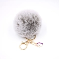 Detailed macro shot of grey fluffy pompom keychain with golden lobster clasp and unicorn charm - Small Unicorn Keychain / Two-tone Grey