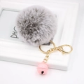 Detailed macro view of a grey faux fur pompom keychain with a pink bell and golden lobster clasp - Two-tone Grey