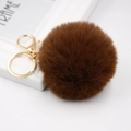 Detailed macro view of an 8cm faux rabbit fur pompom keychain with golden metal clasp - Brown