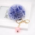 Detail of a fluffy lilac faux fur pompom keychain with a pink bell and golden lobster clasp - Double Blue