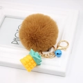 Detail of a brown fluffy faux fur keychain with yellow pineapple charm and gold hardware - Coffee