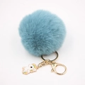 Détail d'un pompon en fausse fourrure bleue avec fermoir doré et breloque licorne - Porte-clés Licorne / Bleu sarcelle