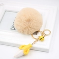 Close-up of yellow banana pendant with apricot faux fur pompom and gold keychain - Nude