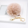 Detailed view of fluffy beige faux fur keychain with gold ring and pearl charm decoration - Mixed Khaki