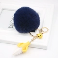 Close-up of a blue faux fur pom-pom with a yellow banana charm and golden metal hardware - Navy Blue