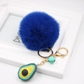 Close-up of a blue faux fur pompom keychain with avocado charm and small bell detail - Avocado Keychain / Sapphire Blue