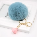Detail of grey-blue fluffy pom-pom keychain with golden metal chain and pink bell charm - Teal