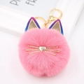Nahaufnahme eines rosa Plüsch-Katzen-Bommel-Schlüsselanhängers mit goldenen Metall-Ohren - Katze mit farbigen Ohren / Dunkelrosa