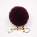 Gros plan d'un porte-clés pompon en fausse fourrure bordeaux avec breloque licorne - Porte-clés Licorne / Fuchsia